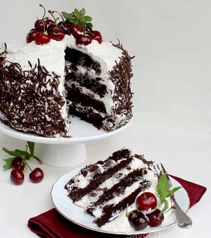 Four layer cake with cherries and whipped cream. 