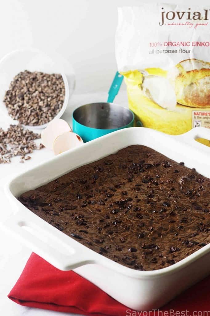 A brownie recipe cooling in a baking pan and einkorn flour in the background. 