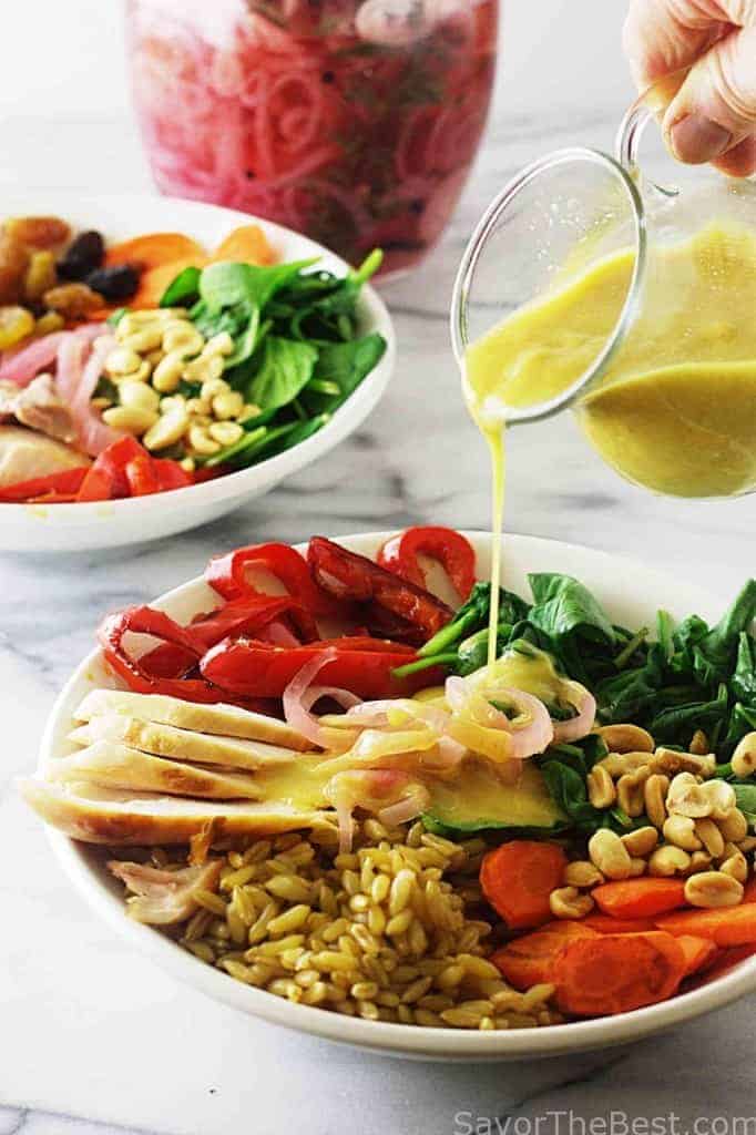 Pouring sauce over an ancient grain bowl with chicken. 