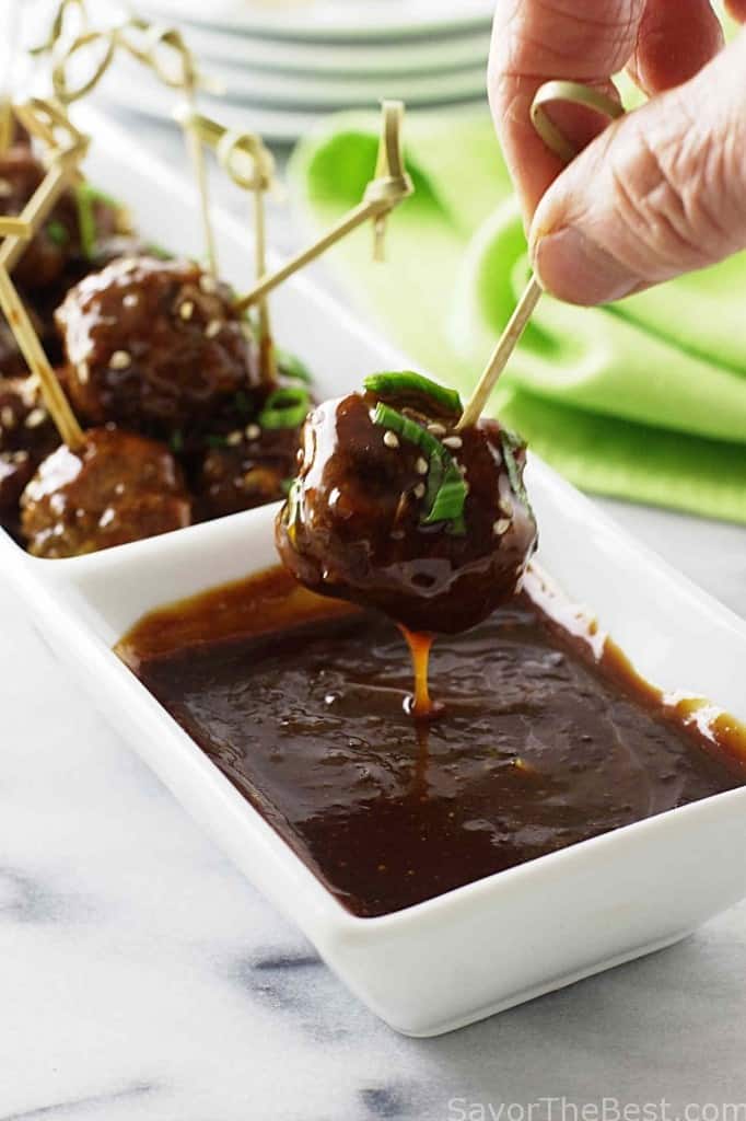 dipping a meatball in sauce. 