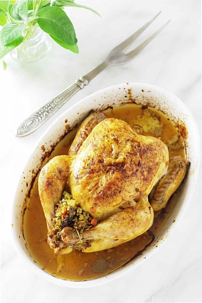 A roasted chicken in a dish stuffed with freekeh. 