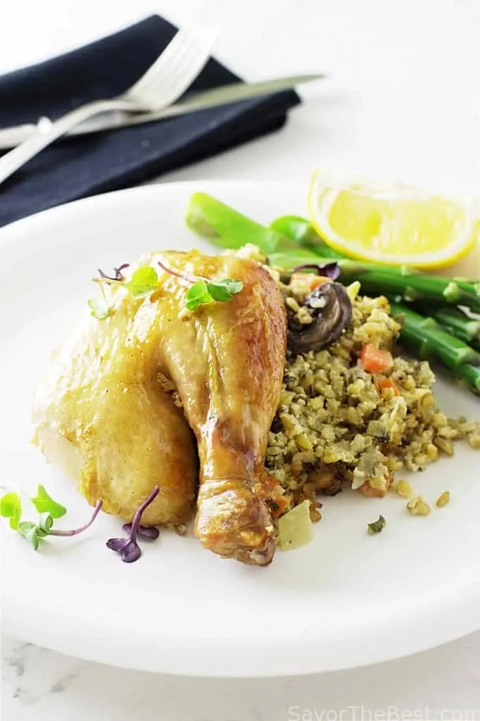 A chicken leg on a plate next to freekeh and asparagus.