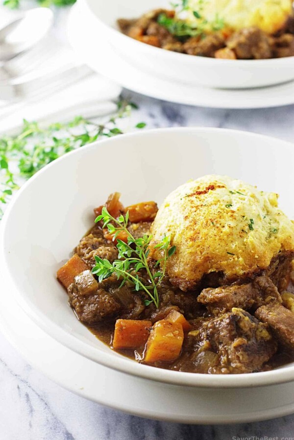 A serving bowl filled with a casserole and topped with a dumpling.