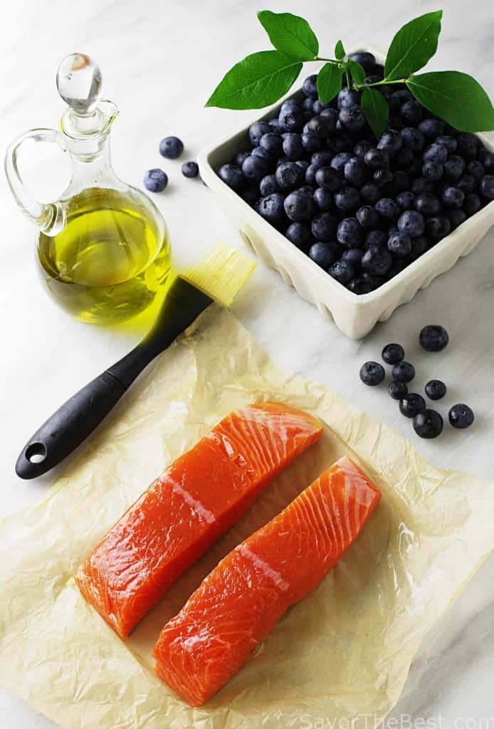 King salmon fillets with fresh blueberries and a jar of olive oil. 