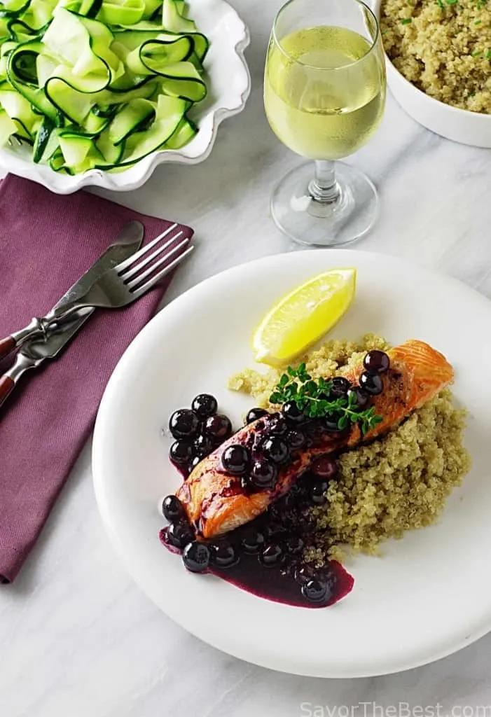A serving plate with salmon, blueberry sauce, and quinoa. 