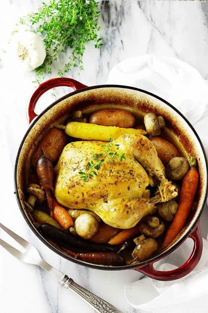 A whole chicken in a Dutch oven with vegetables. 