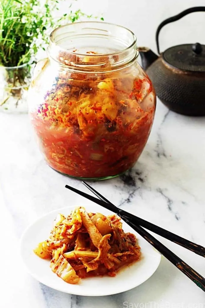 Kimchee in a jar next to chopsticks. 