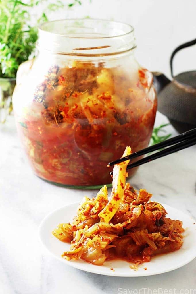 A plate of kimchee with a jar in the background. 