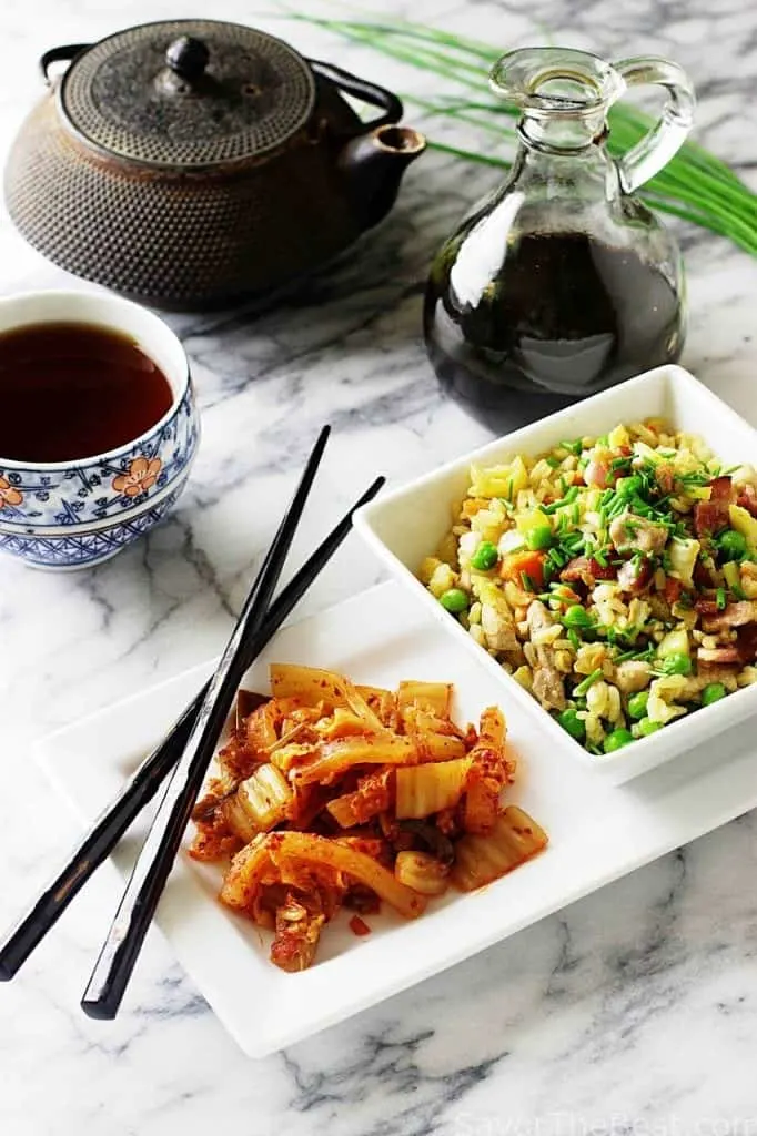 Kimchi next to a bowl of fried rice and tea. 