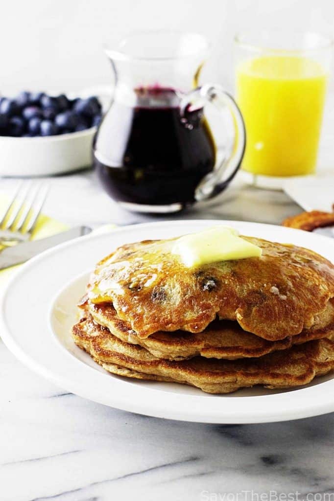 A stack of einkorn pancakes with blueberry syrup in the background. 