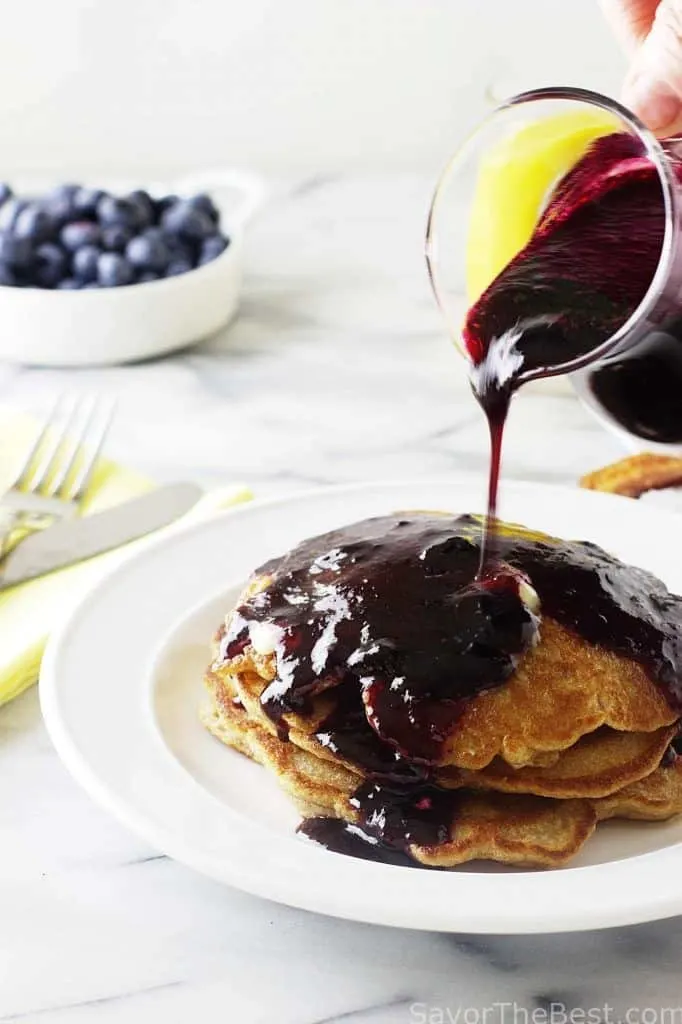 A stack of pancakes with blueberry syrup.