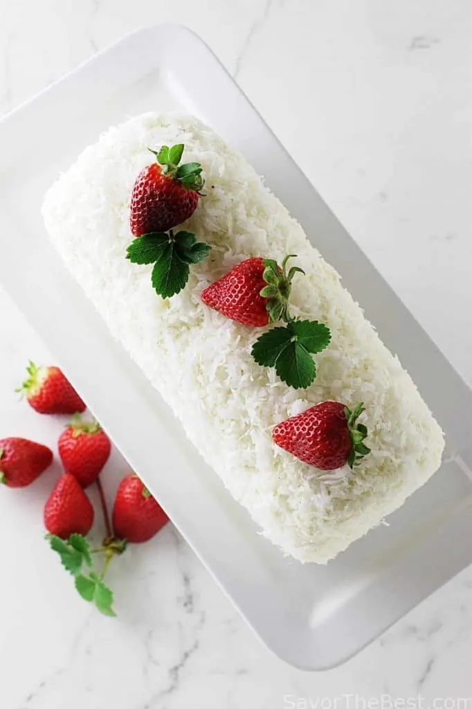 overhead photo of a coconut cake roll with strawberries on top