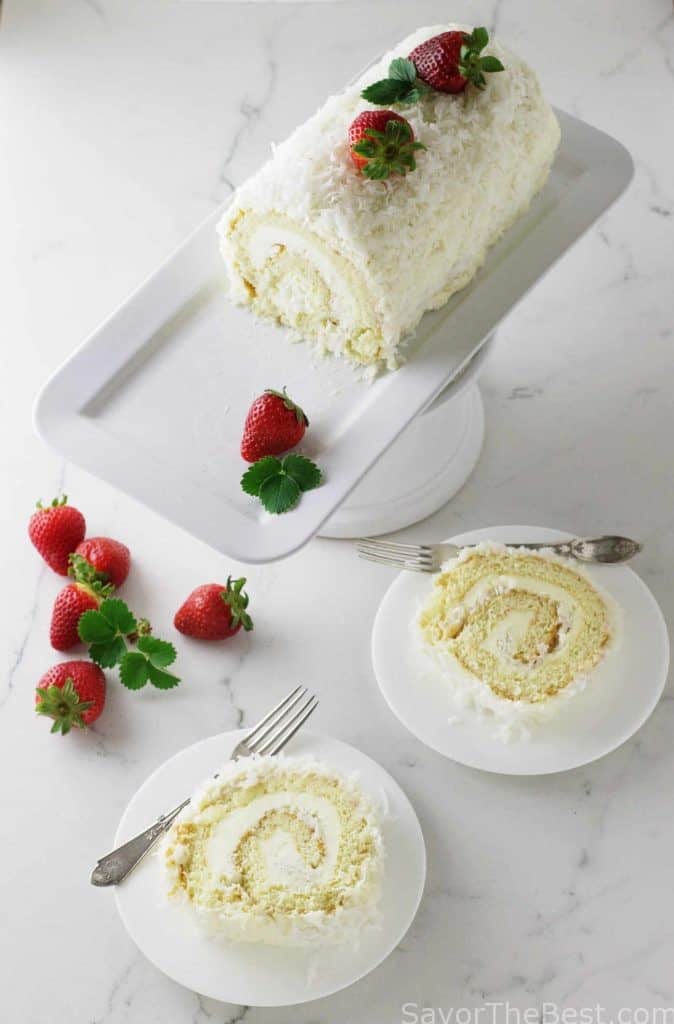 A cake roll on a platter with two slices of cake next to the platter