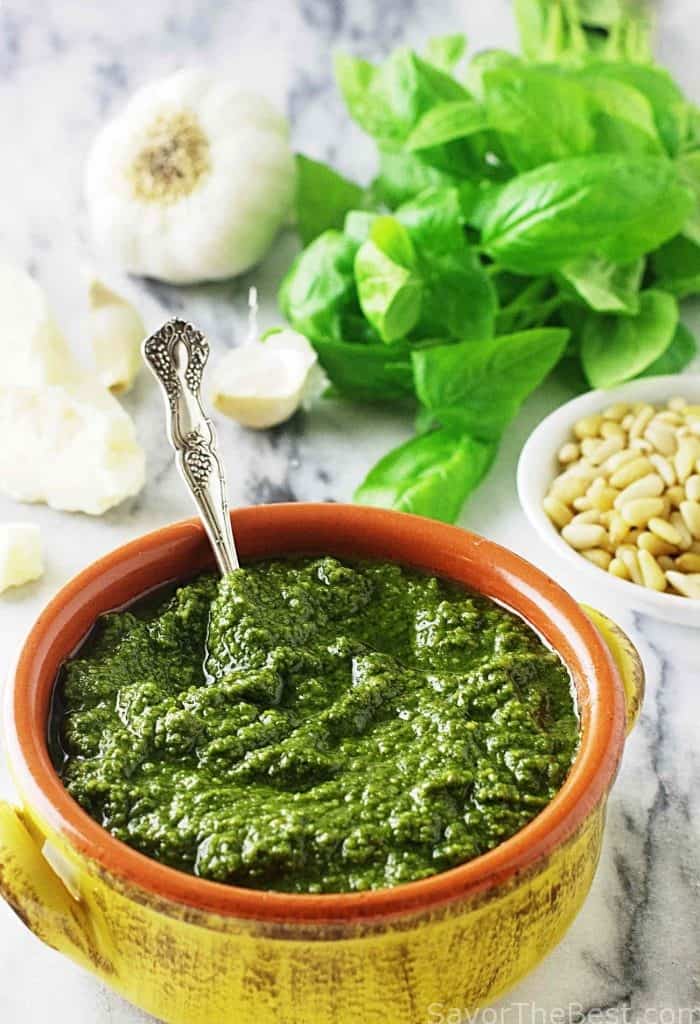 A spoon in a bowl of basil pesto.