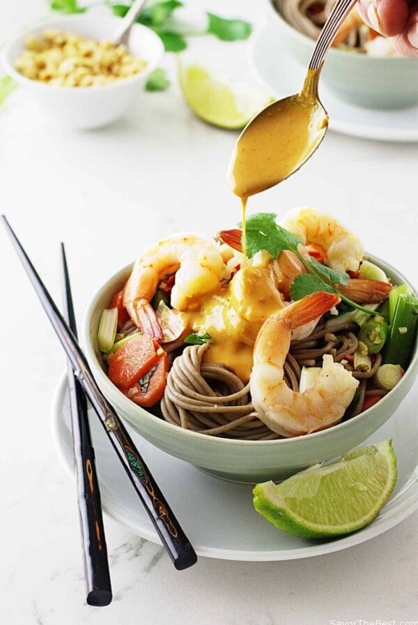 Pouring peanut sauce on a shrimp noodle bowl.