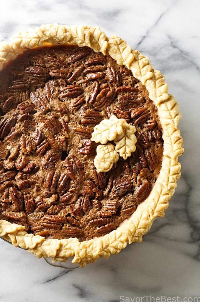 A chocolate and pecan pie in a standard pie dish on a marble counter.