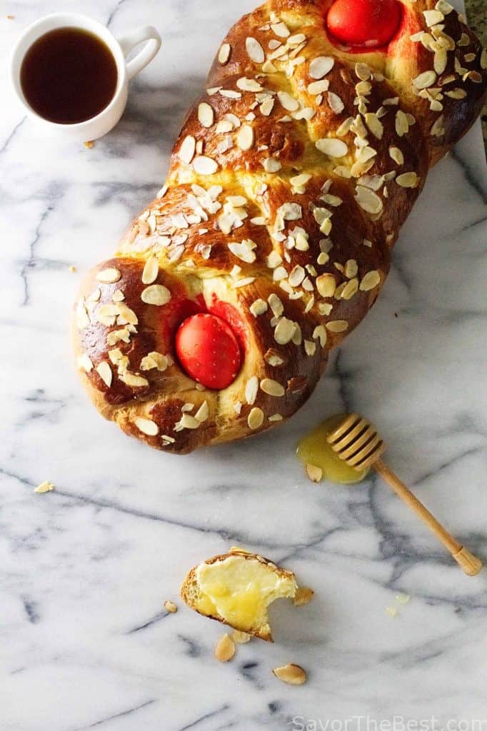 A loaf of Greek Easter bread next to a cup of coffee. 