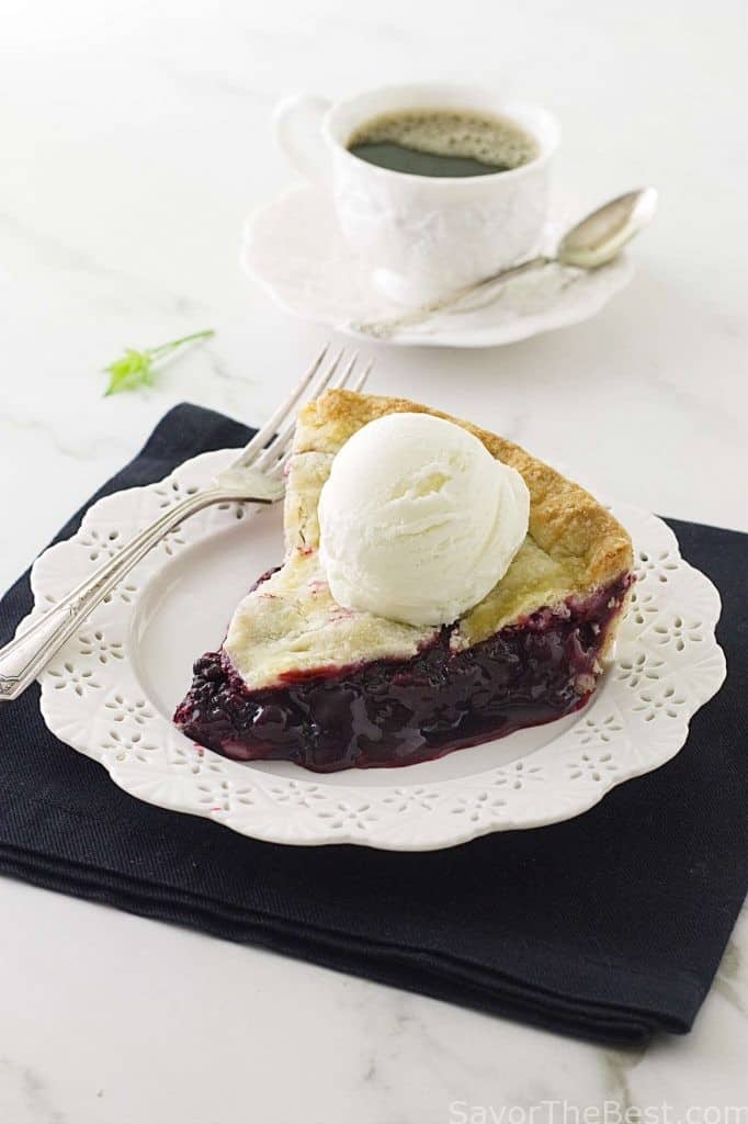 A slice of blackberry pie with ice cream on top. 