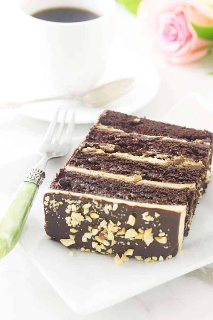 a slice of chocolate peanut butter layer cake on a white plate with a green fork. 