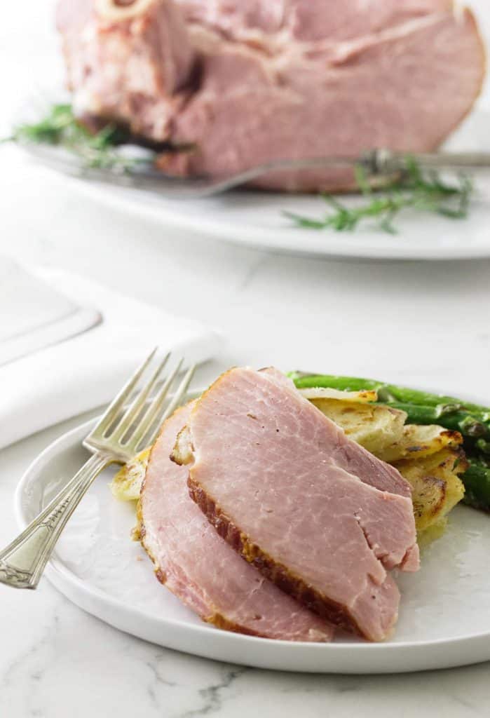 Two Spiral Ham slices on a plate with potatoes and asparagus