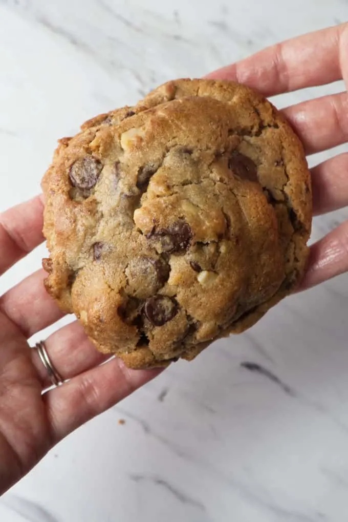 Two hands holding a Levain bakery chocolate chip cookie