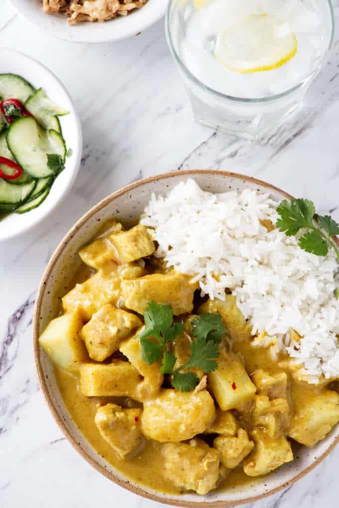 A bowl of Curry Chicken with rice and a glass of ice water