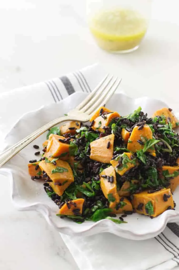 A plate with black rice, sweet potato and kale salad. 