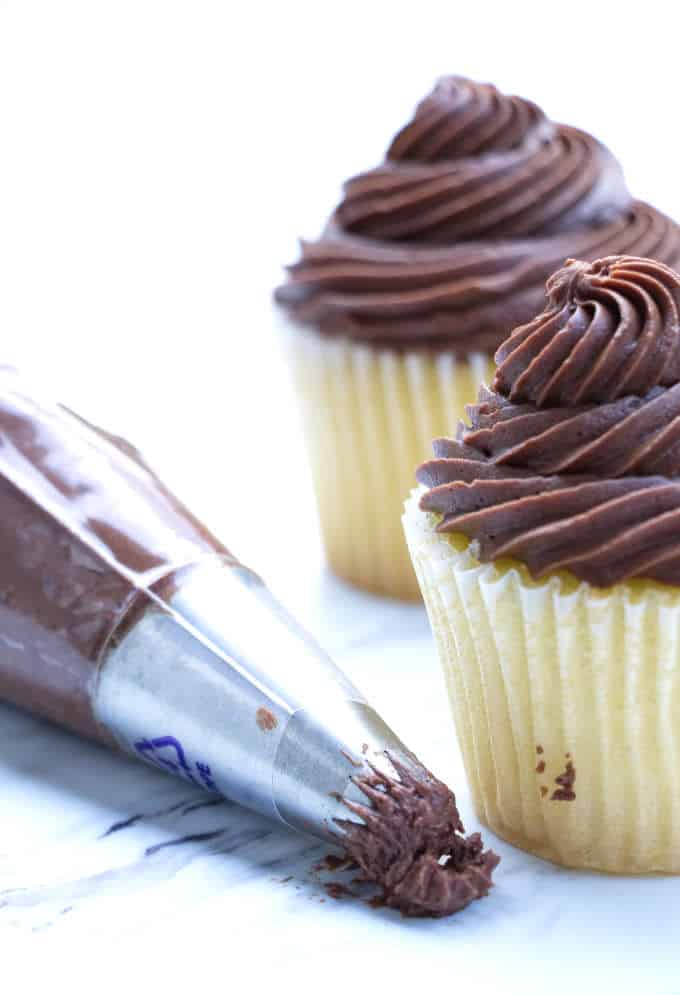 two vanilla cupcakes with chocolate frosting