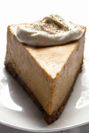 Close up of a slice of Pumpkin Spiced cheesecake, with whipped cream dollop on top.