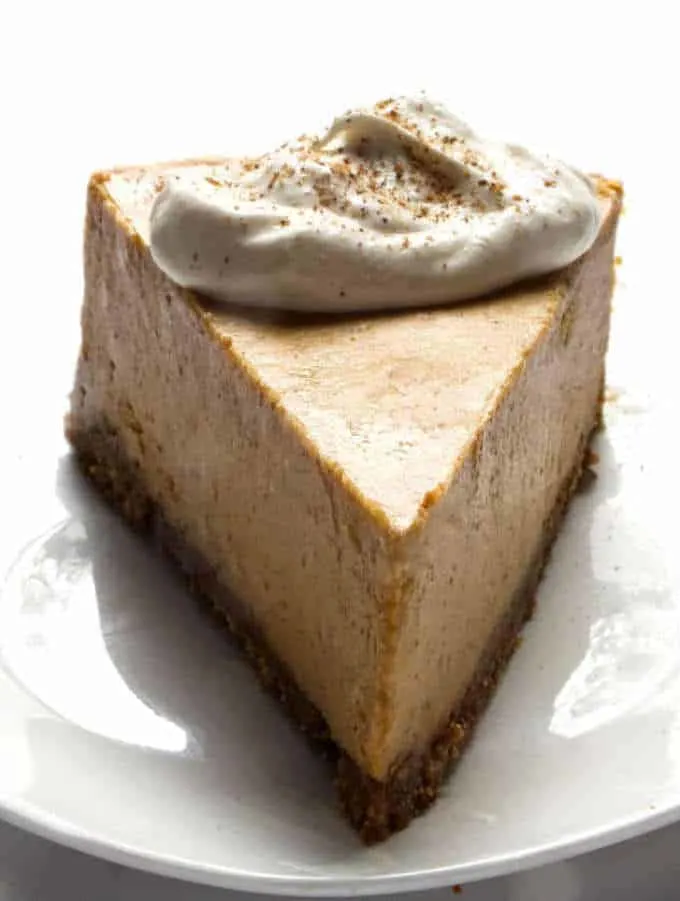 Close up of a slice of Pumpkin Spiced cheesecake, with whipped cream dollop on top.