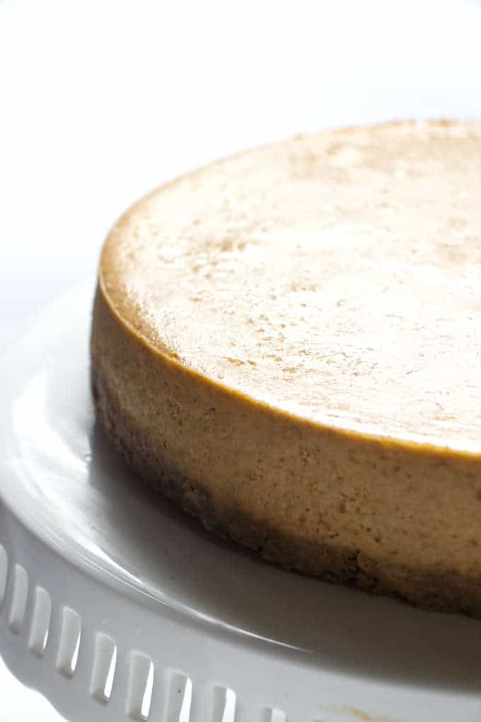 Close up of a freshly baked pumpkin spice cheesecake on a cake stand.