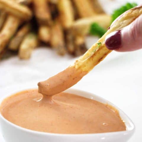French fry being dipped into fry sauce