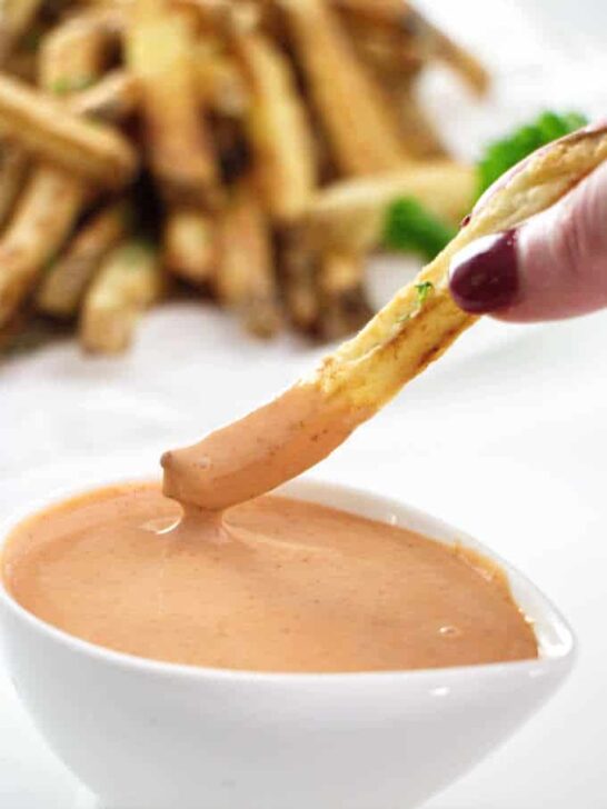 French fry being dipped into fry sauce