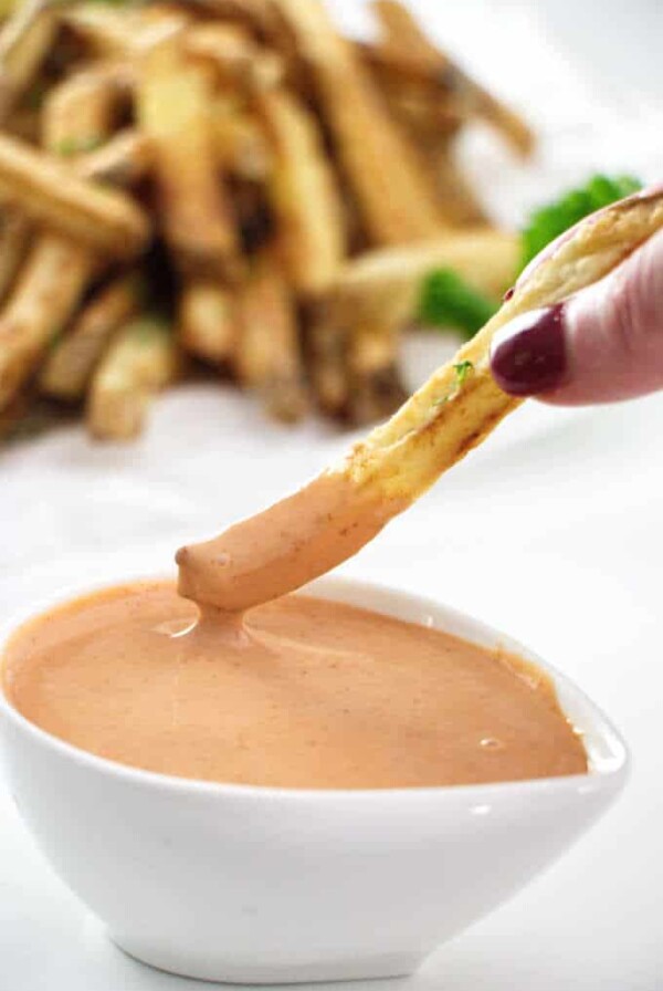 French fry being dipped into fry sauce