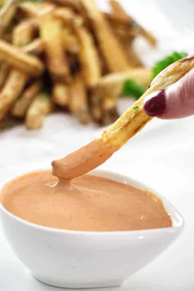 French fry being dipped into fry sauce