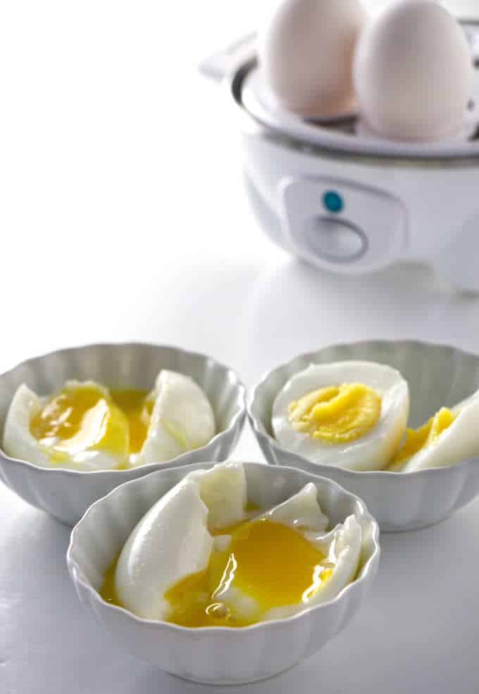 an egg cooker with shelled eggs in front