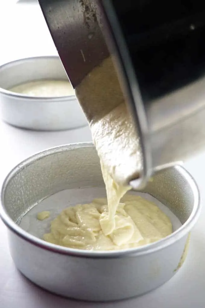 yellow cake batter being poured into a 6-inch cake pan