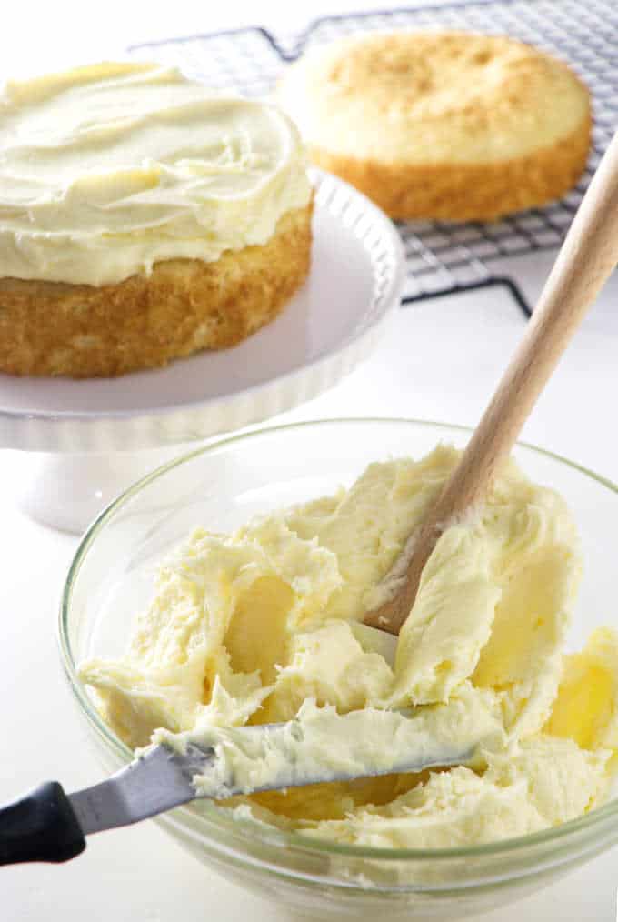 a bowl of cake filling with cake layers in the background