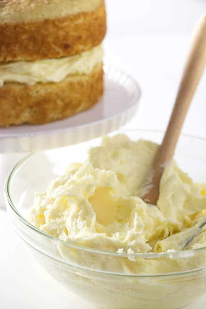 a bowl of cake filling with a cake in the background