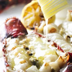 close up of a grilled lobster tail being drizzled with garlic butter sauce