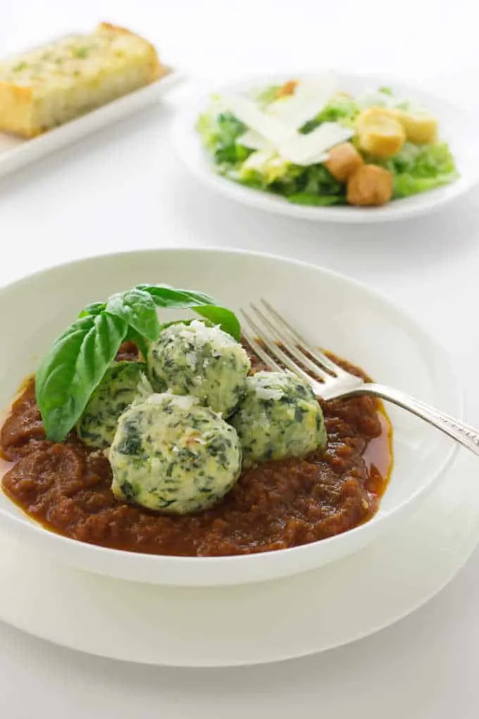 Malfatti in Tomato-Garlic Sauce with a salad in the background. 