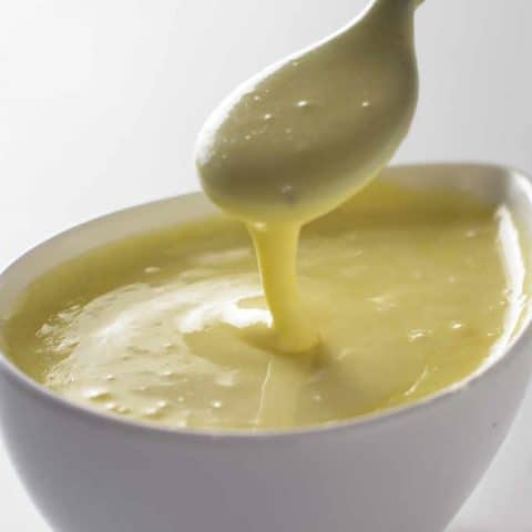 a dish of hollandaise sauce with a spoon in the dish