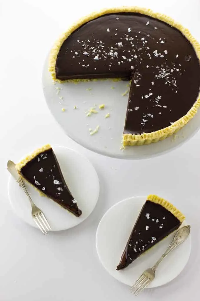 Chocolate Caramel Tart on a cake plate with two slices below on small plates