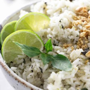 A bowl of basil lime rice with sliced limes in the background