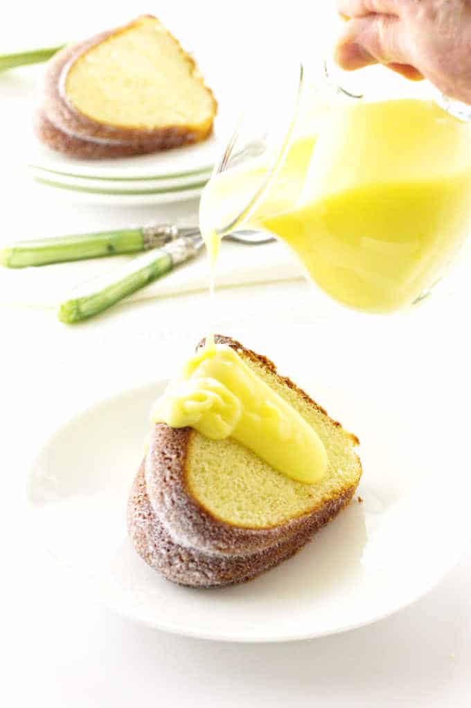 A slice of lemon Bundt cake with lemon dessert sauce being poured