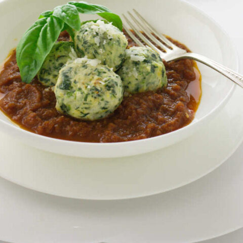 Three malfatti dumplings in tomato sauce.
