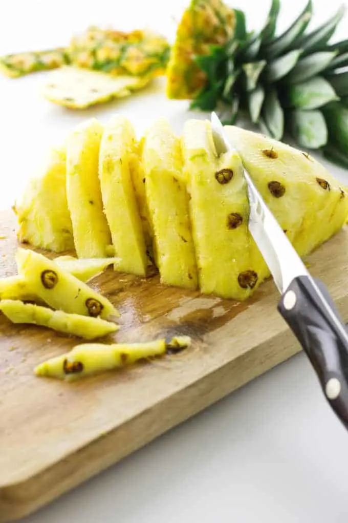 Fresh pineapple with knife removing the eyes