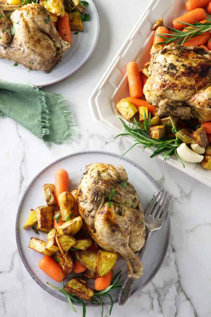 overhead view of Cornish game hens on a platter and two serving plates