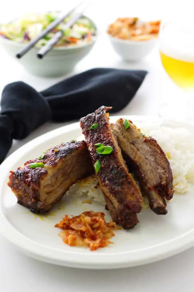 Serving of 3 Korean-style Pork Ribs, Rice, Kimchee..glass of beer and sides of kimchee slaw and kimchi