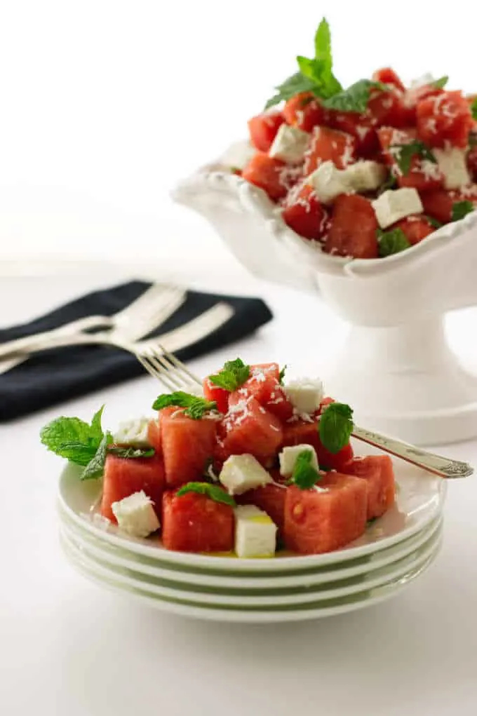 Serving of salad on stack of plates, bowl of salad, napkin/forks